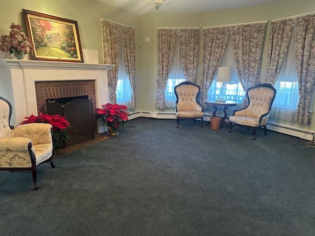 Elegant living room with fireplace, floral chairs, and large curtained windows