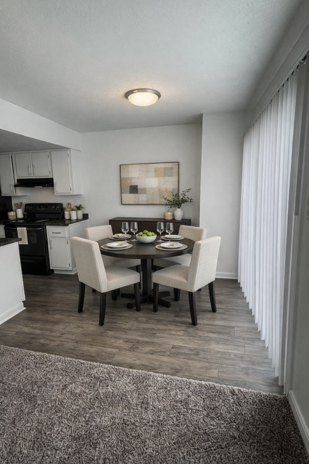 Small dining area with round table, four chairs, and a view into a compact kitchen.