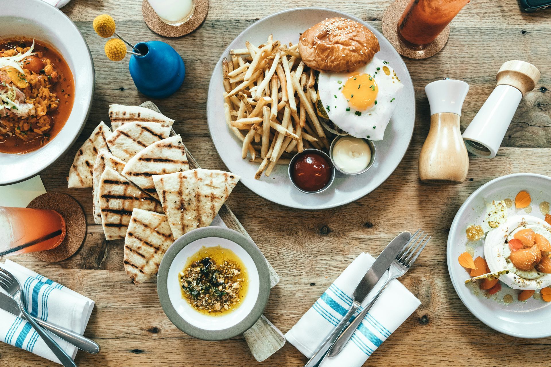 Breakfast spread with eggs, toast, fries, soup, and coffee on a rustic wooden table
