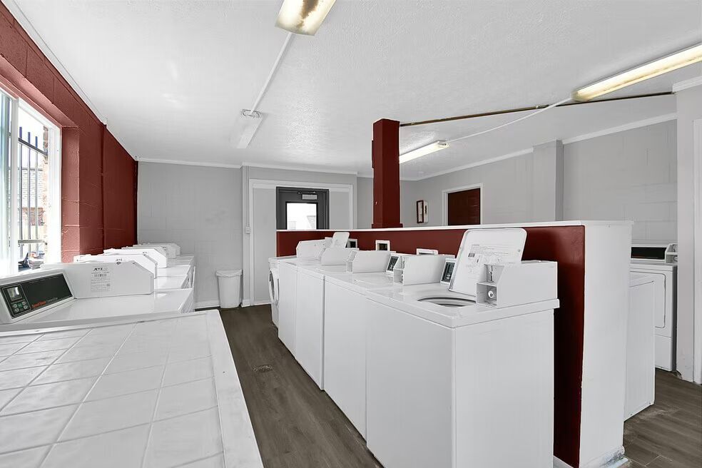 Laundry room with white washers and dryers, wood flooring, and a large window