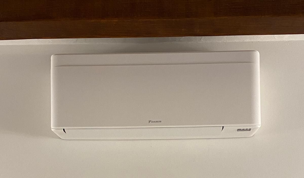 Condizionatore d'aria bianco a parete su una parete beige.