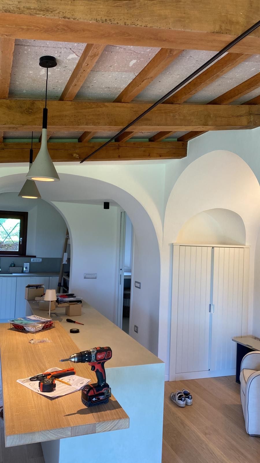Cucina moderna con travi a vista in legno, penisola, lampada a sospensione e nicchie ad arco nelle pareti.