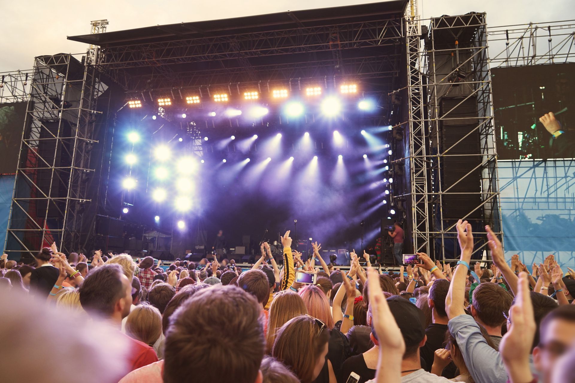 A crowd of people are standing in front of a stage at a concert.