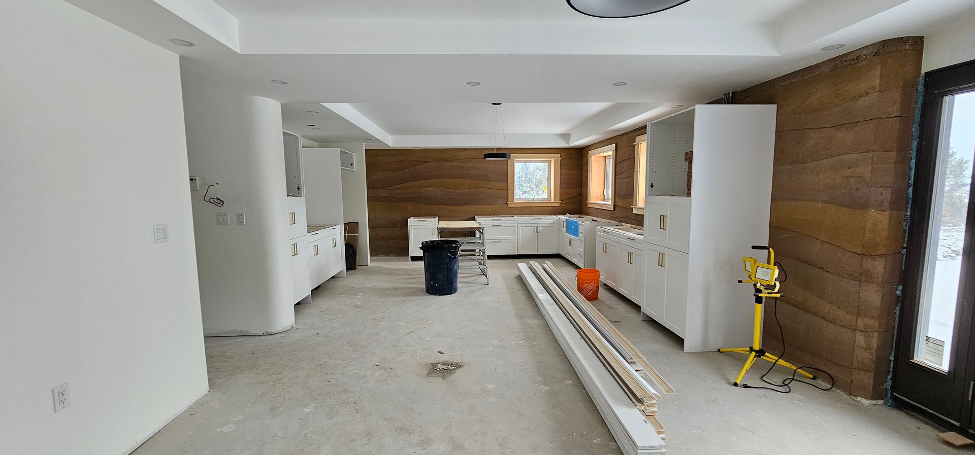 A large empty room with white cabinets and a wooden wall.