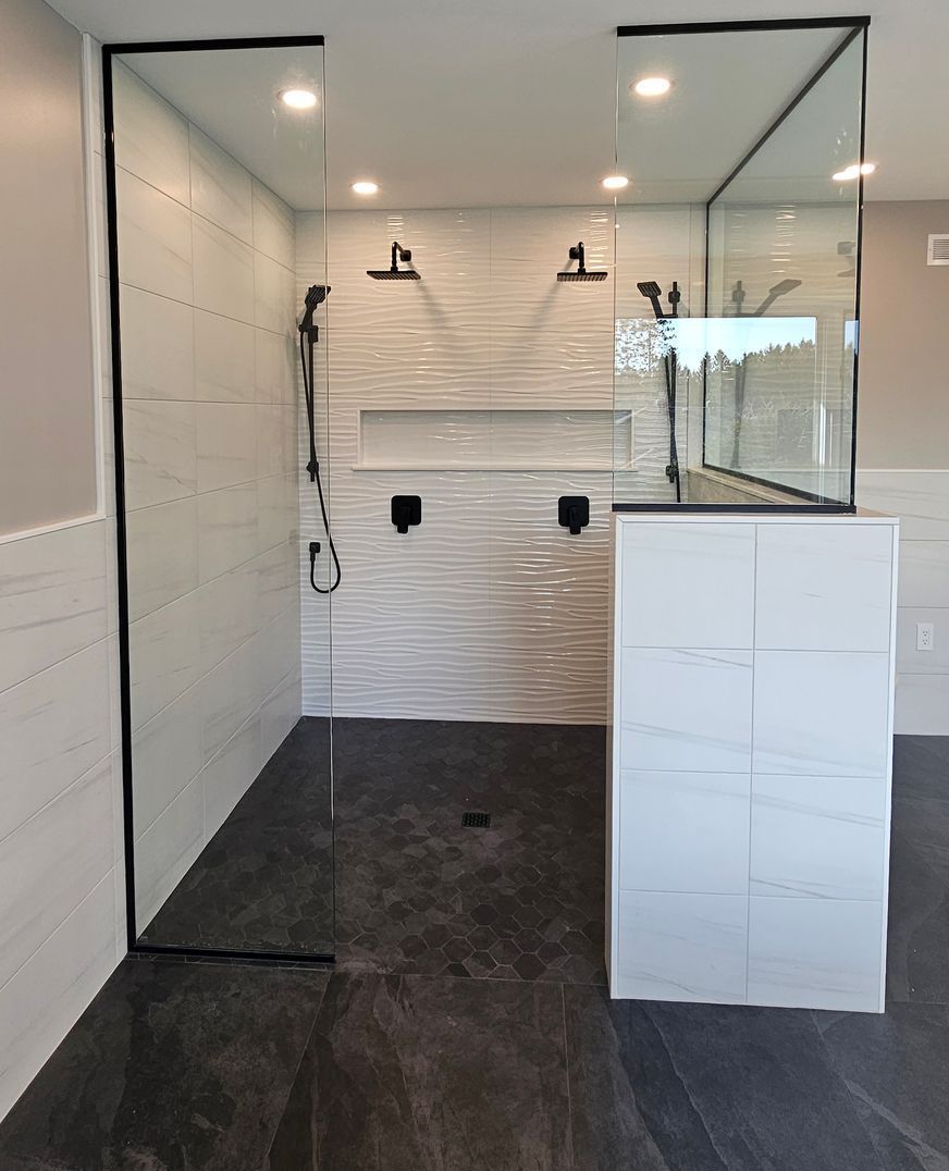 A bathroom with a walk in shower and a black floor.