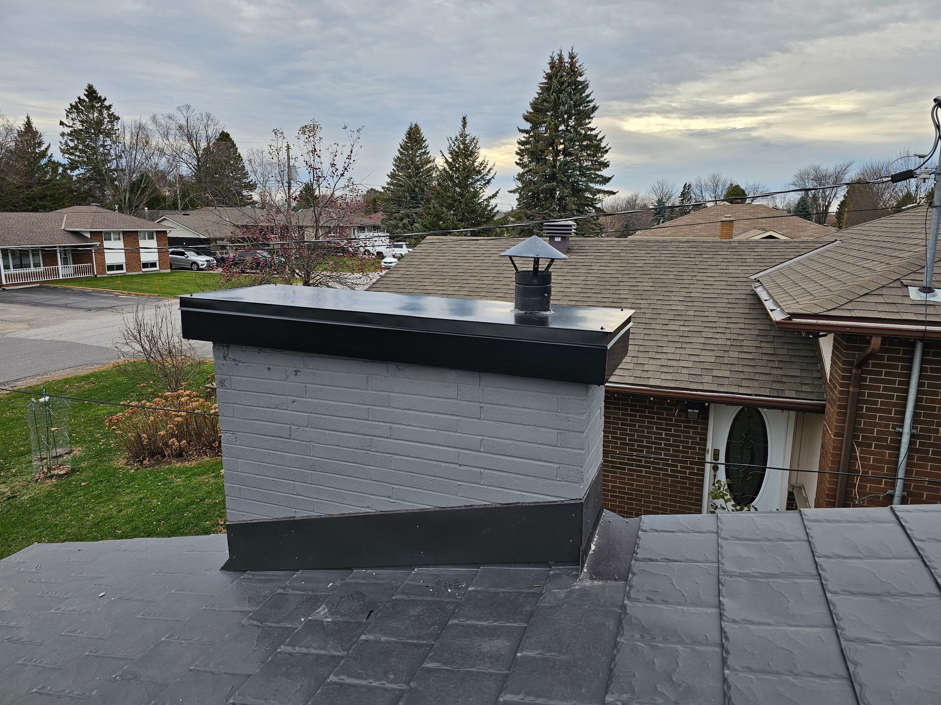 Two construction workers are working on the roof of a building.