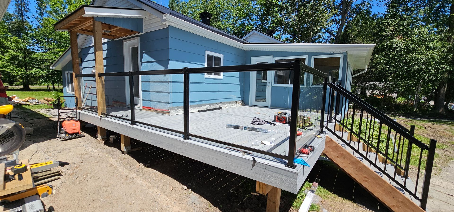 A blue house with a deck and stairs in front of it.