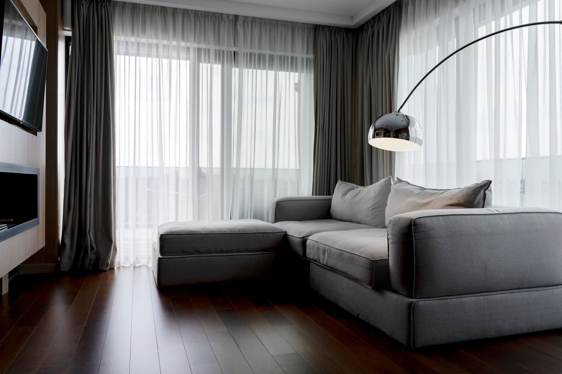 A living room with a couch , lamp , television and curtains.