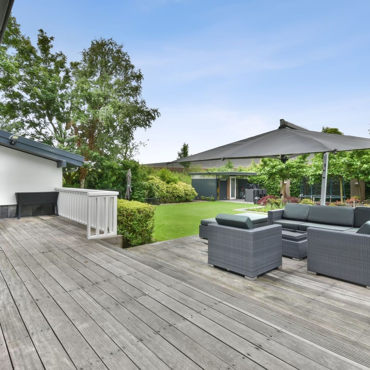 A wooden deck with a couch and chairs under an umbrella