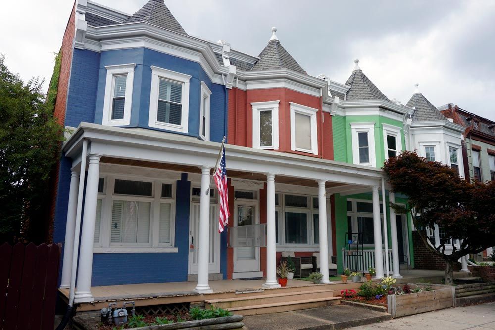 a row of colorful houses with an american flag on the front porch .
