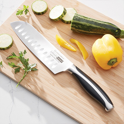 Chef’s knife on cutting board with sliced zucchini, yellow pepper, and parsley