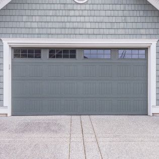 Gray two-car garage door with small upper windows on a house exterior