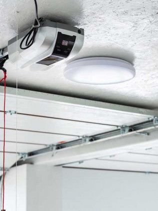 Ceiling-mounted garage door opener with a round light fixture and visible tracks.