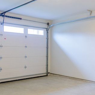 Empty white garage with closed overhead door and concrete floor