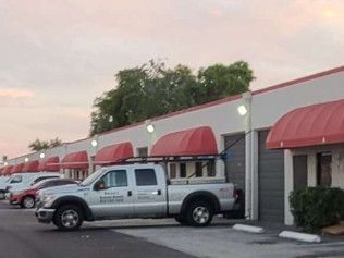 Silver pickup truck parked outside a strip mall with red awnings at dusk