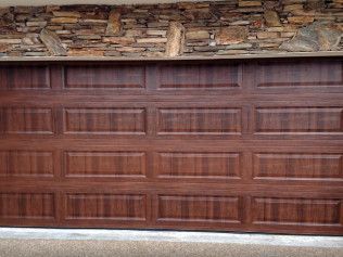 Wooden garage door with stone trim along the top edge