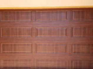 Wood-paneled garage door with four horizontal sections and a tan trim above.
