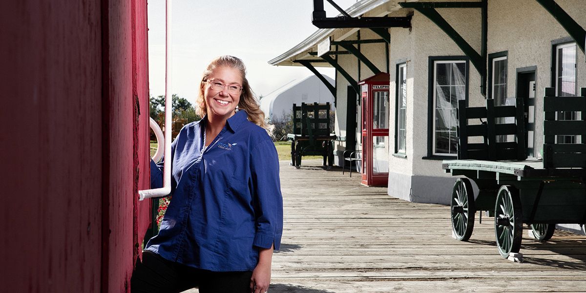 Angela Richmond, Vision CU loan administrator, poses with a vintage passenger train in Stettler, AB.