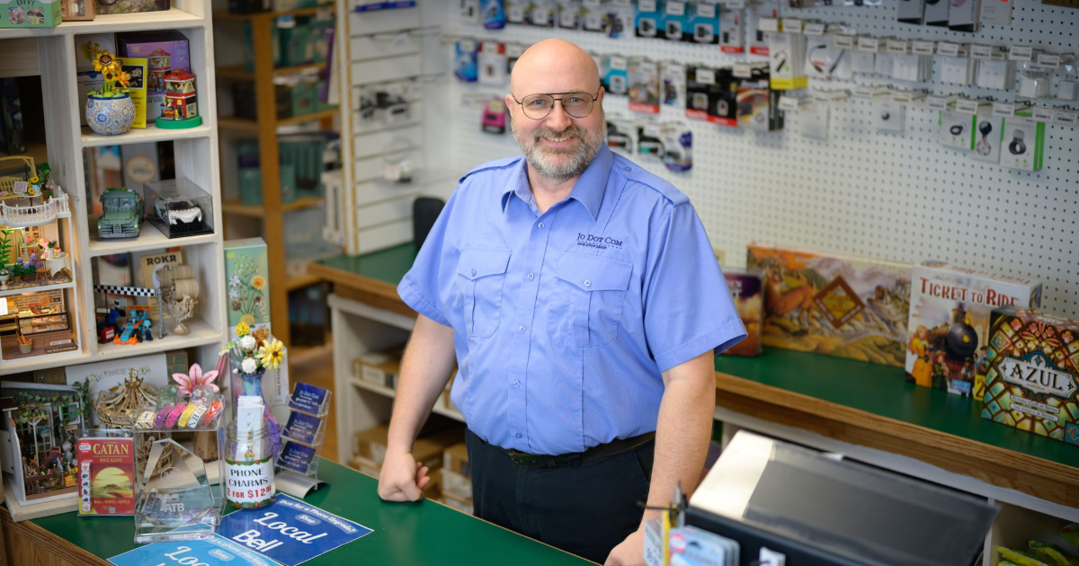 A store owner stands behind the counter in a local shop with electronics and games.