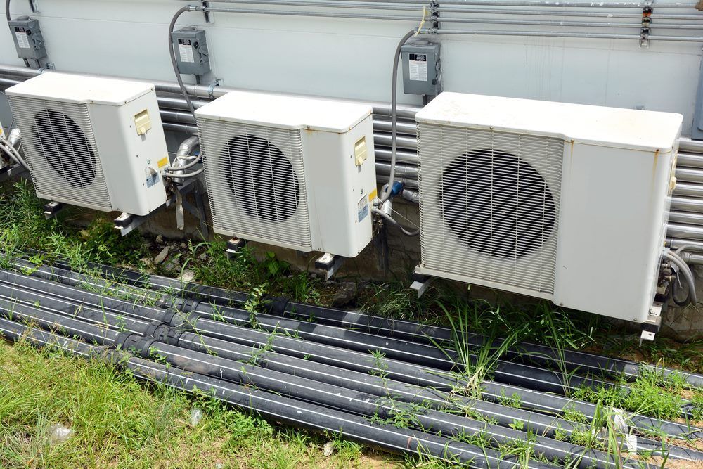 Three Air Conditioners Are Sitting Next to Each Other on the Side —​ Centre Evap & Home Maintenance Services in Ciccone, NT