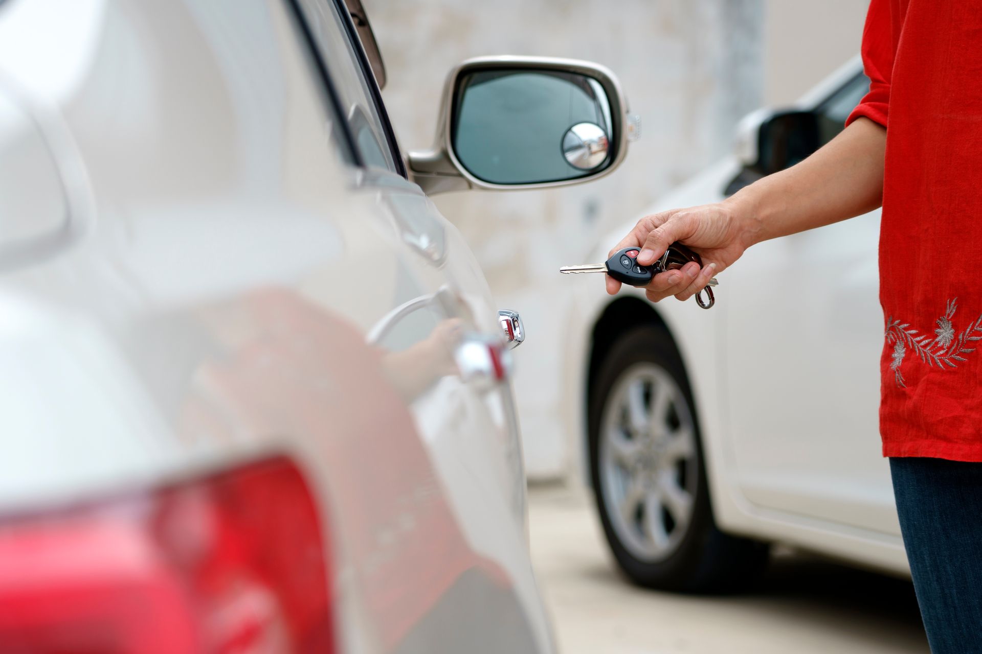 Person in red shirt unlocking a white car with a key outdoors. — GA Plant & Automotive Repairs In Taminda, NSW
