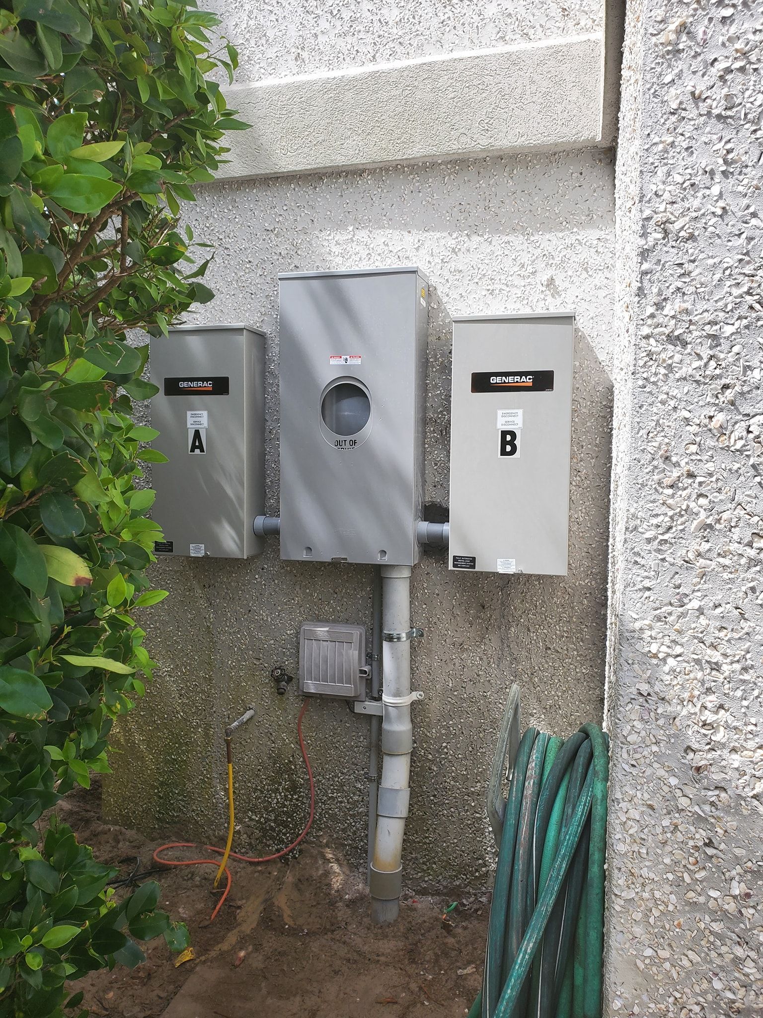 A wall-mounted electrical meter box sits between two gray panels labeled A and B on a textured beige exterior wall.