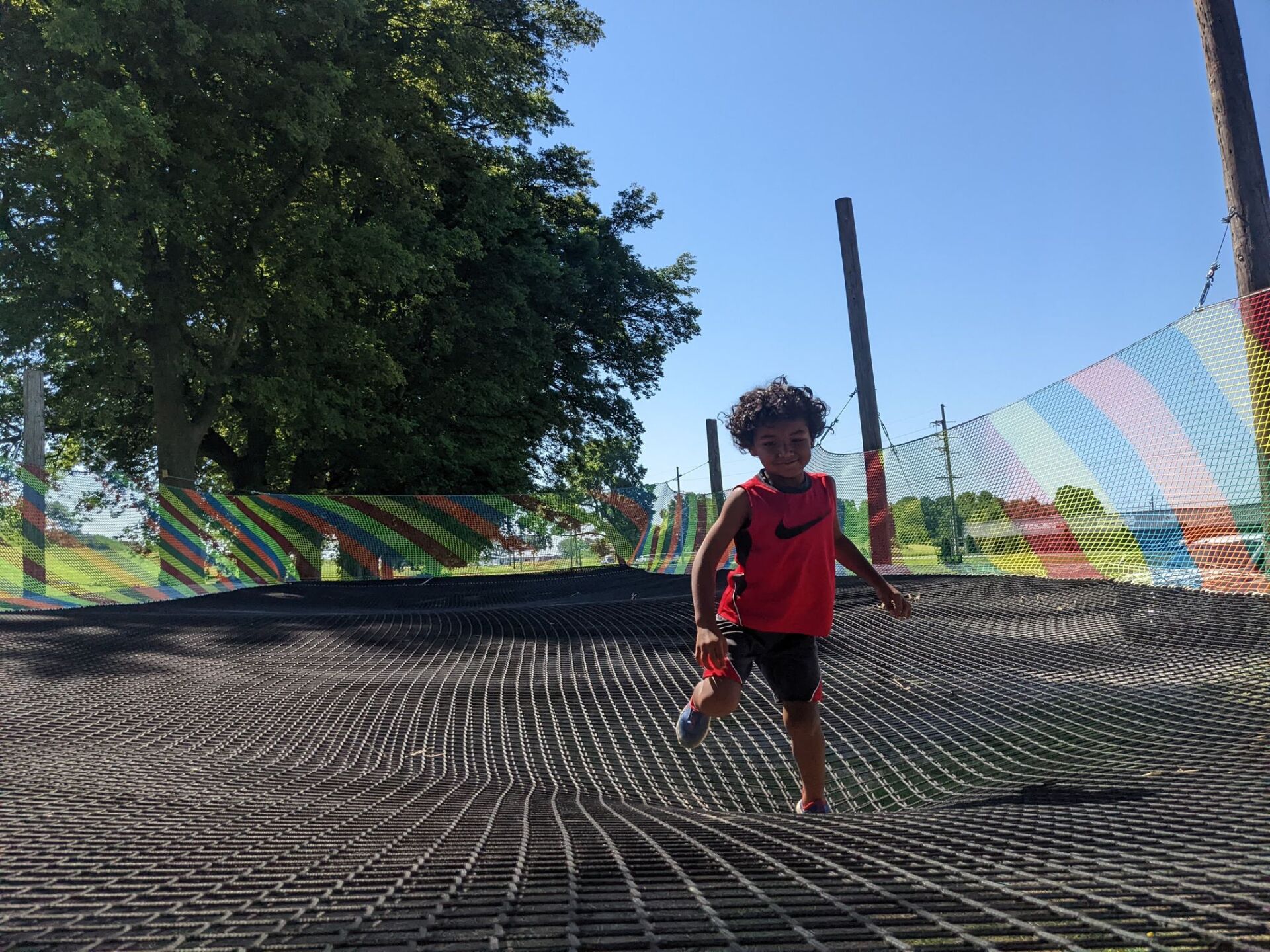 A young boy in a red nike shirt is running on a trampoline