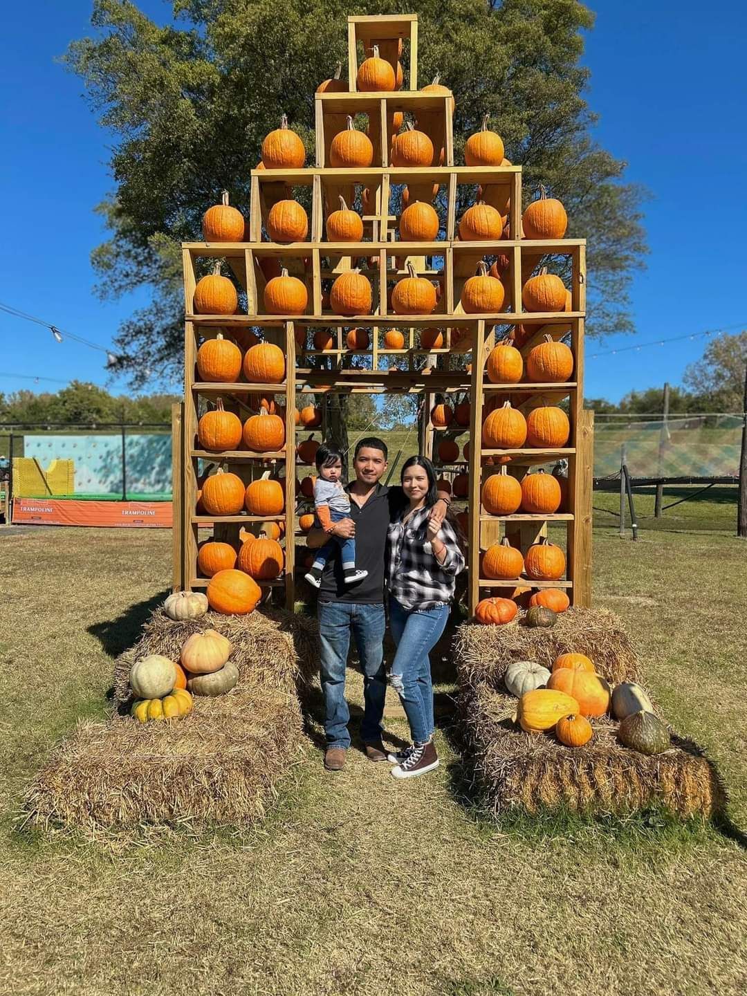 Two children are standing in front of a pyramid of pumpkins.