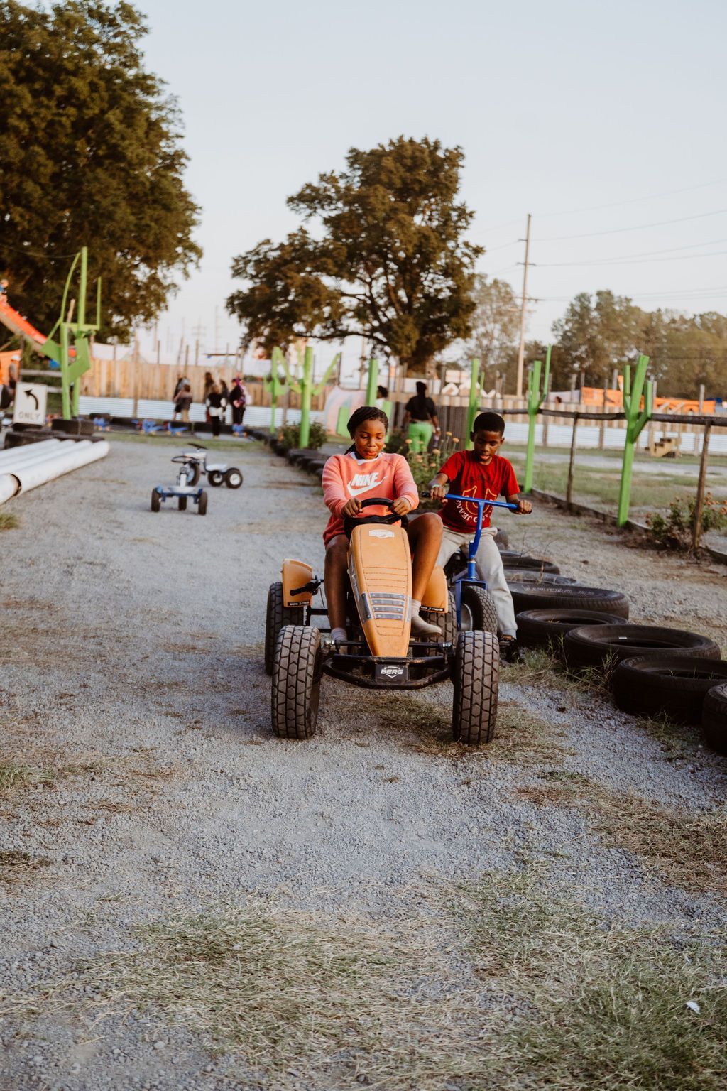 A woman is riding a pedal cart on a tricycle track.