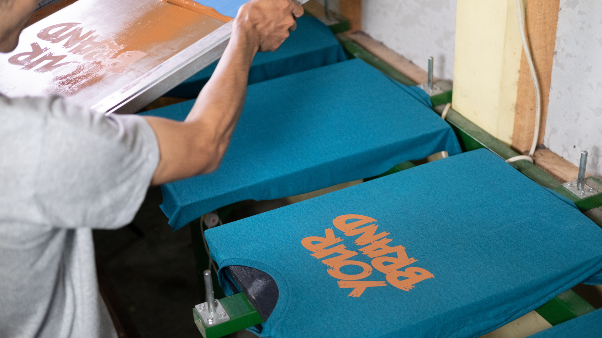 Person screen printing shirts with the words