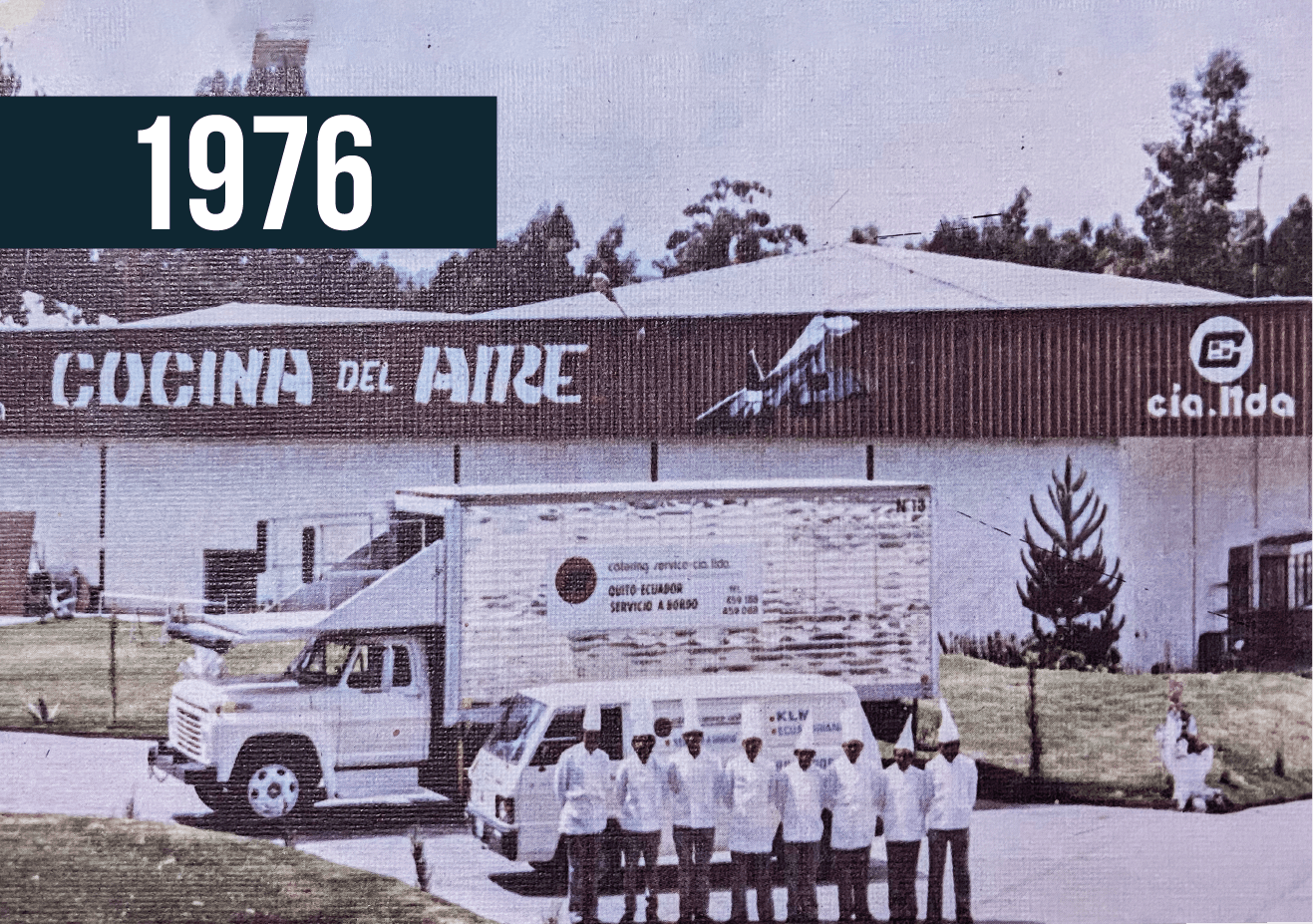 Vista de 1976 de una fábrica de Coca-Cola con un camión y trabajadores de pie frente a ella.