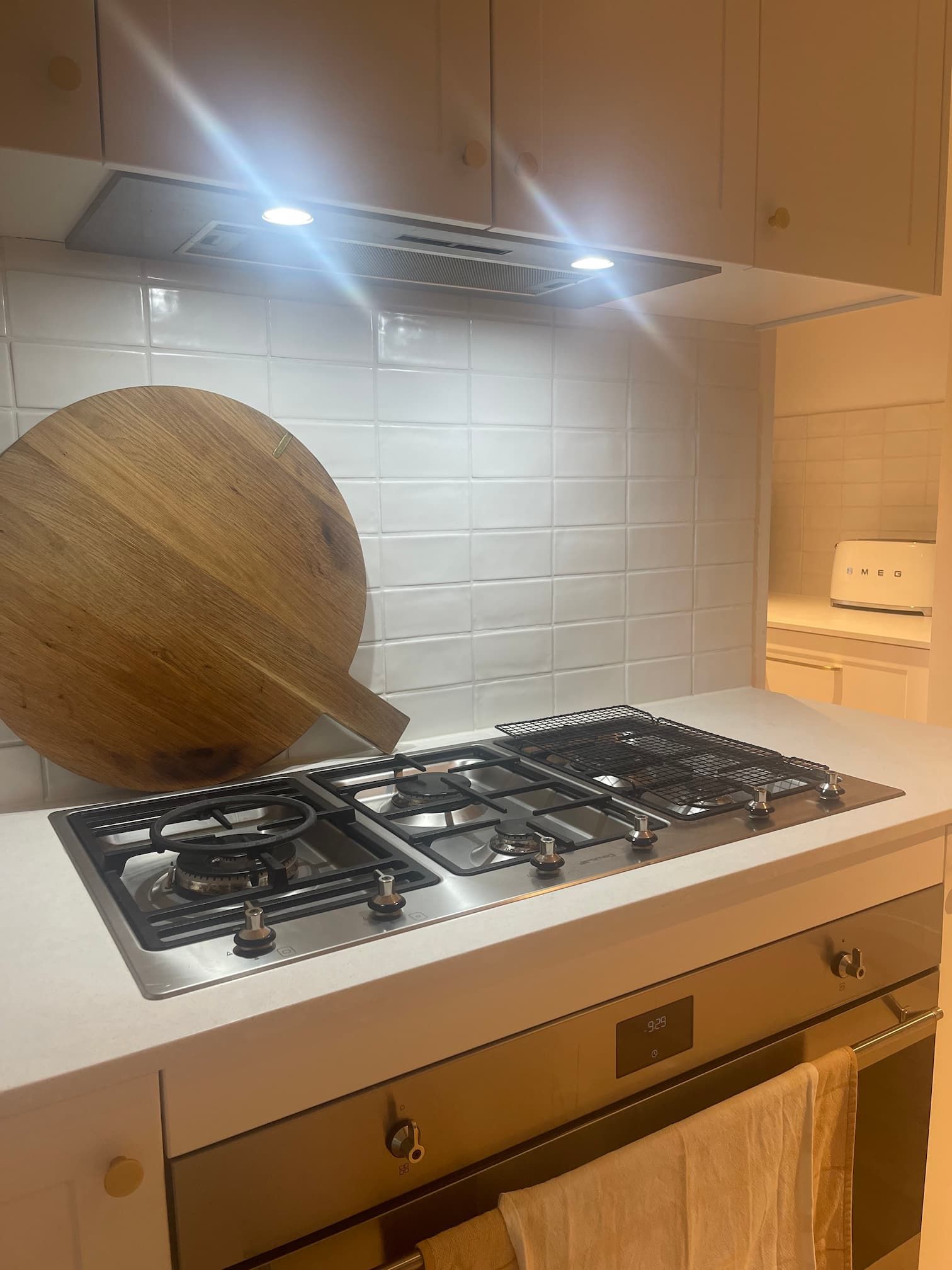 Kitchen with stainless steel gas stovetop and oven, white countertops, and white subway tile backsplash.