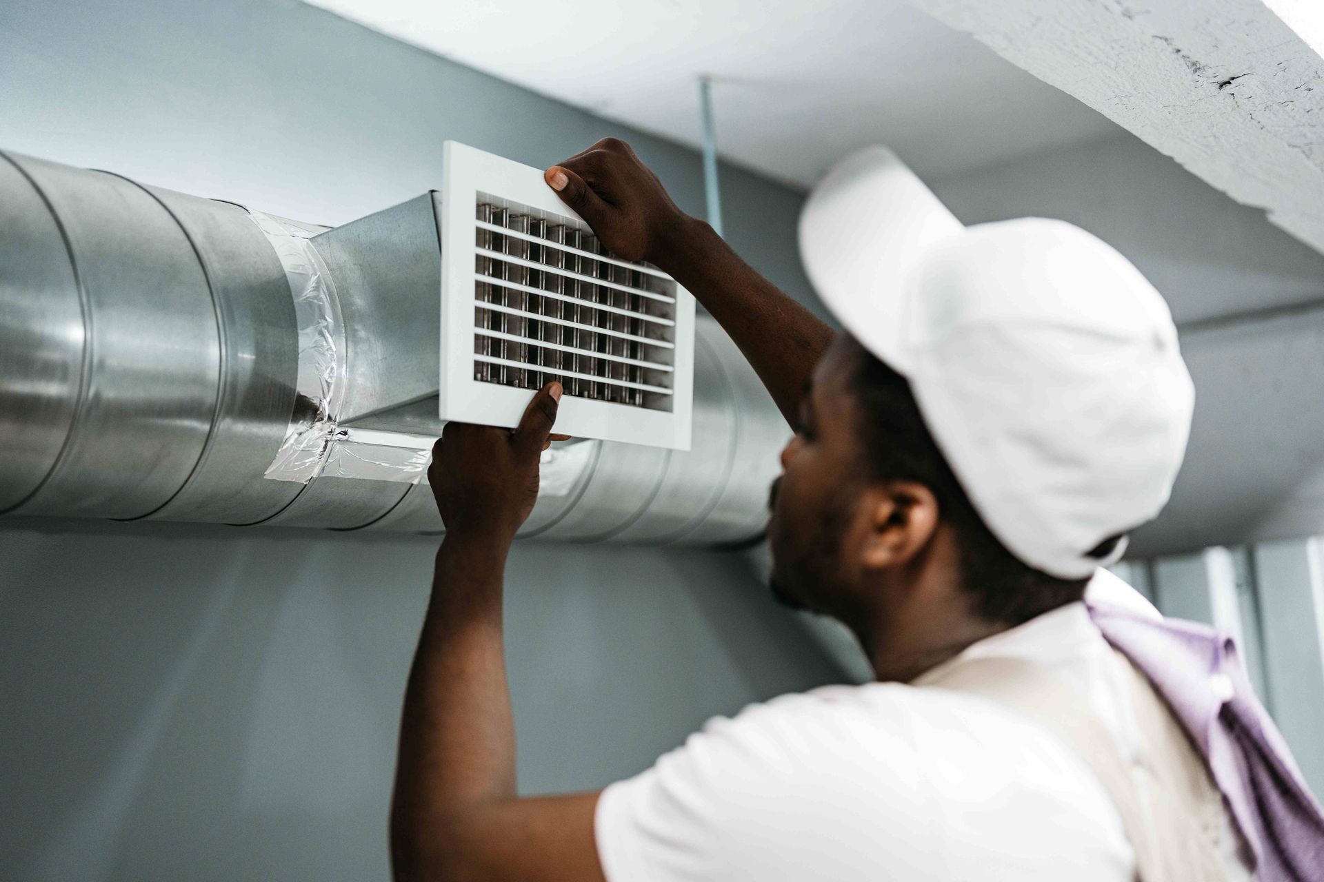 Worker installing air duct vent.