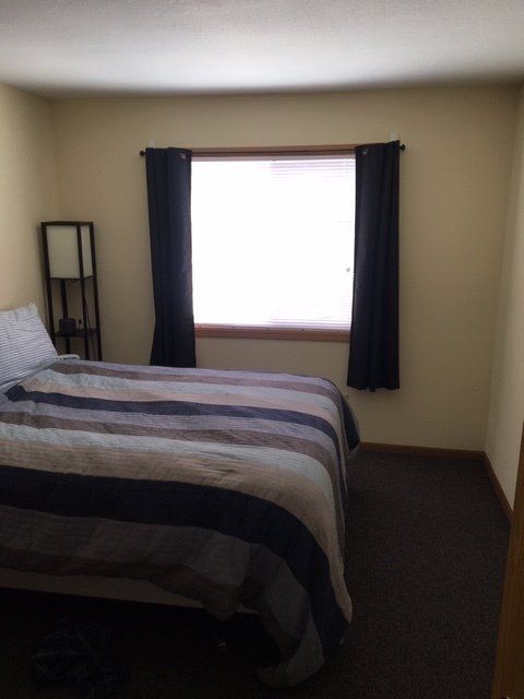 Bedroom with queen bed, lamp, and curtains for example purposes.