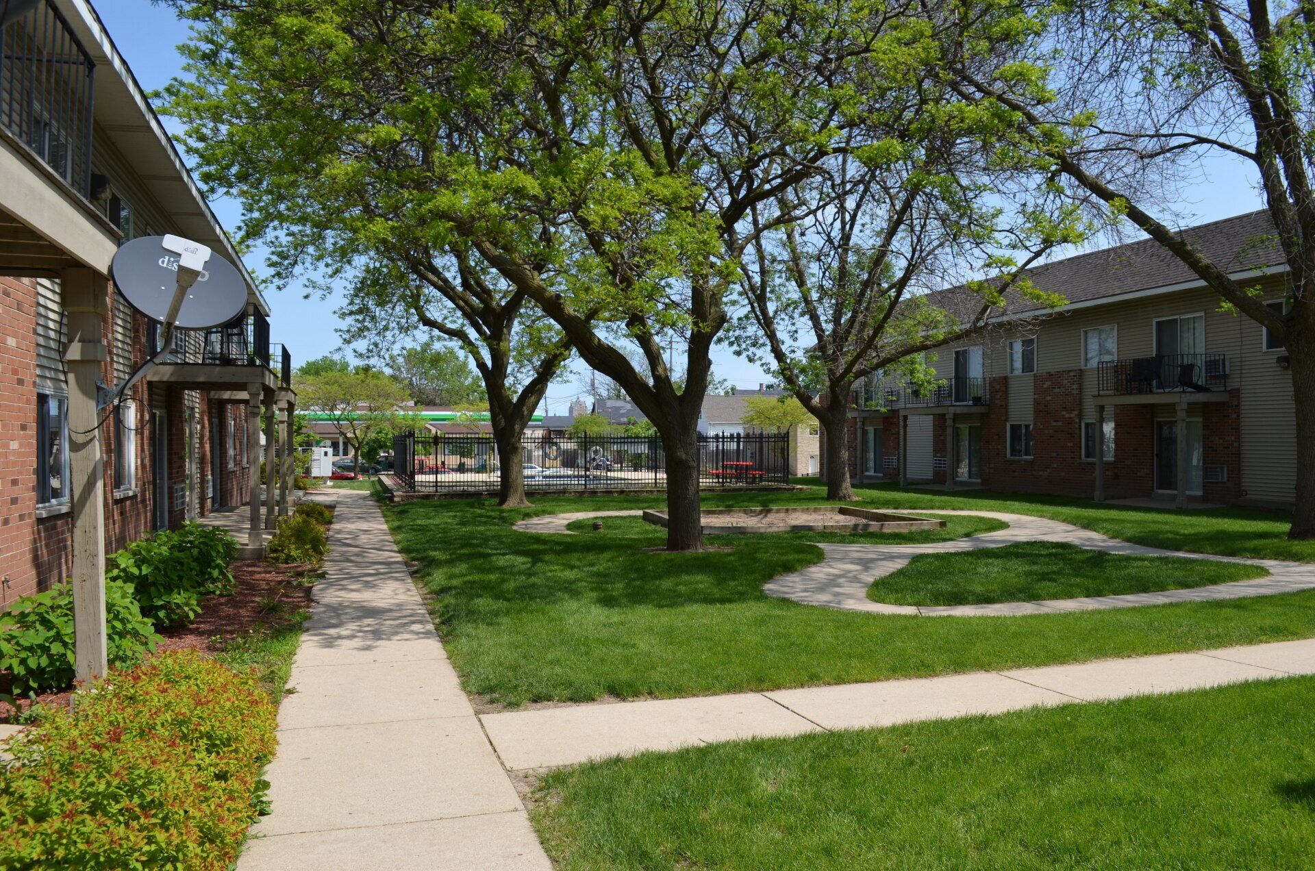 Golden Domes Apartments property with green grass, pathways, and trees.
