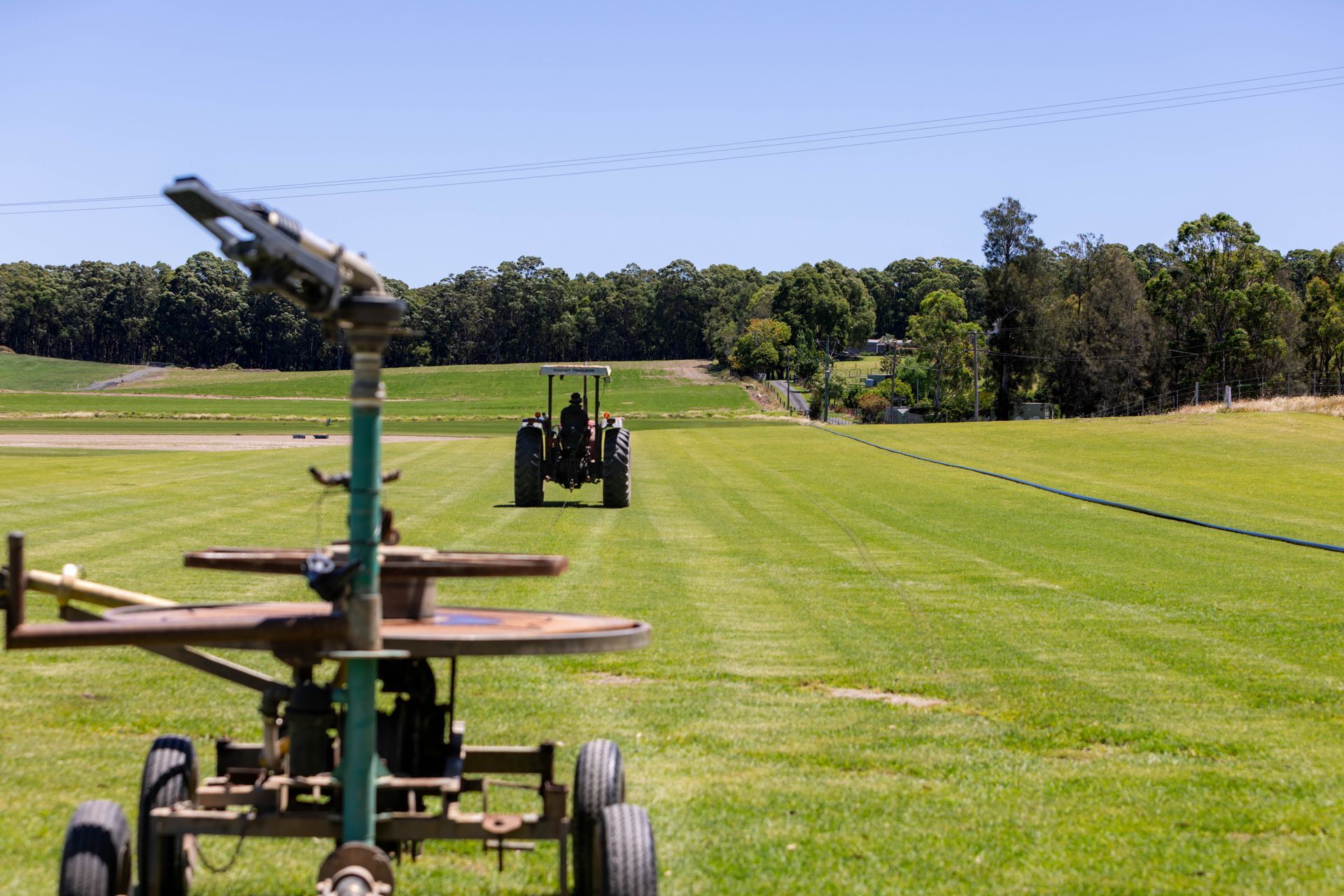 Irrigation equipment in a green field; trees in background under blue sky | Ryans Turf