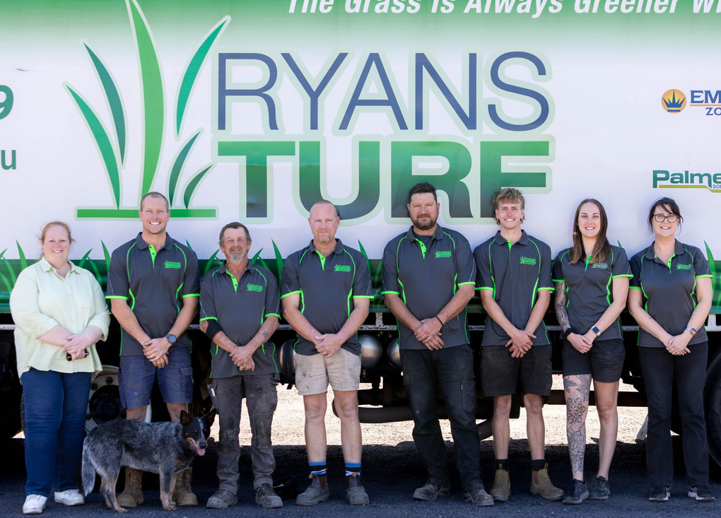 Ryans Turf team stands in front of their truck, wearing grey and green uniforms.