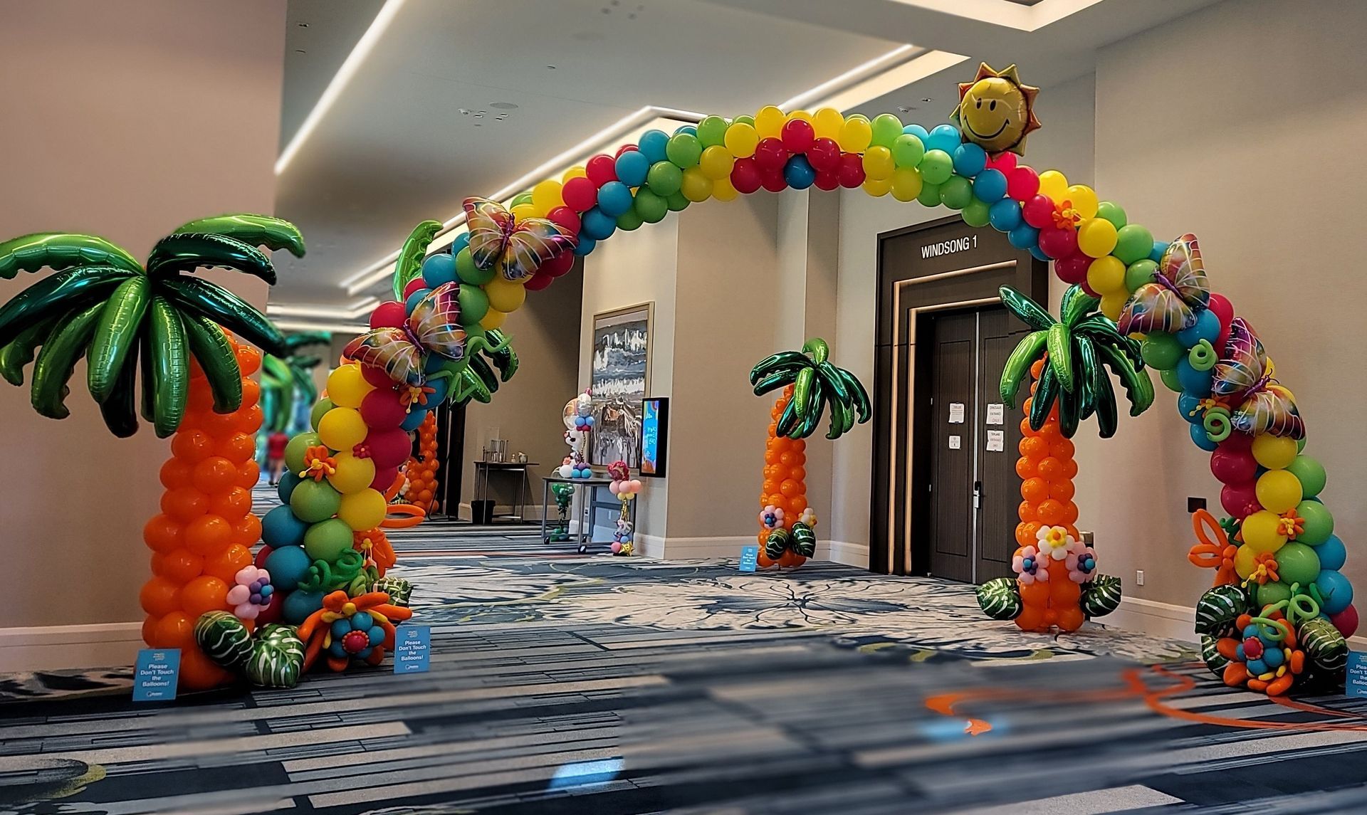 a room decorated with balloons and palm trees .