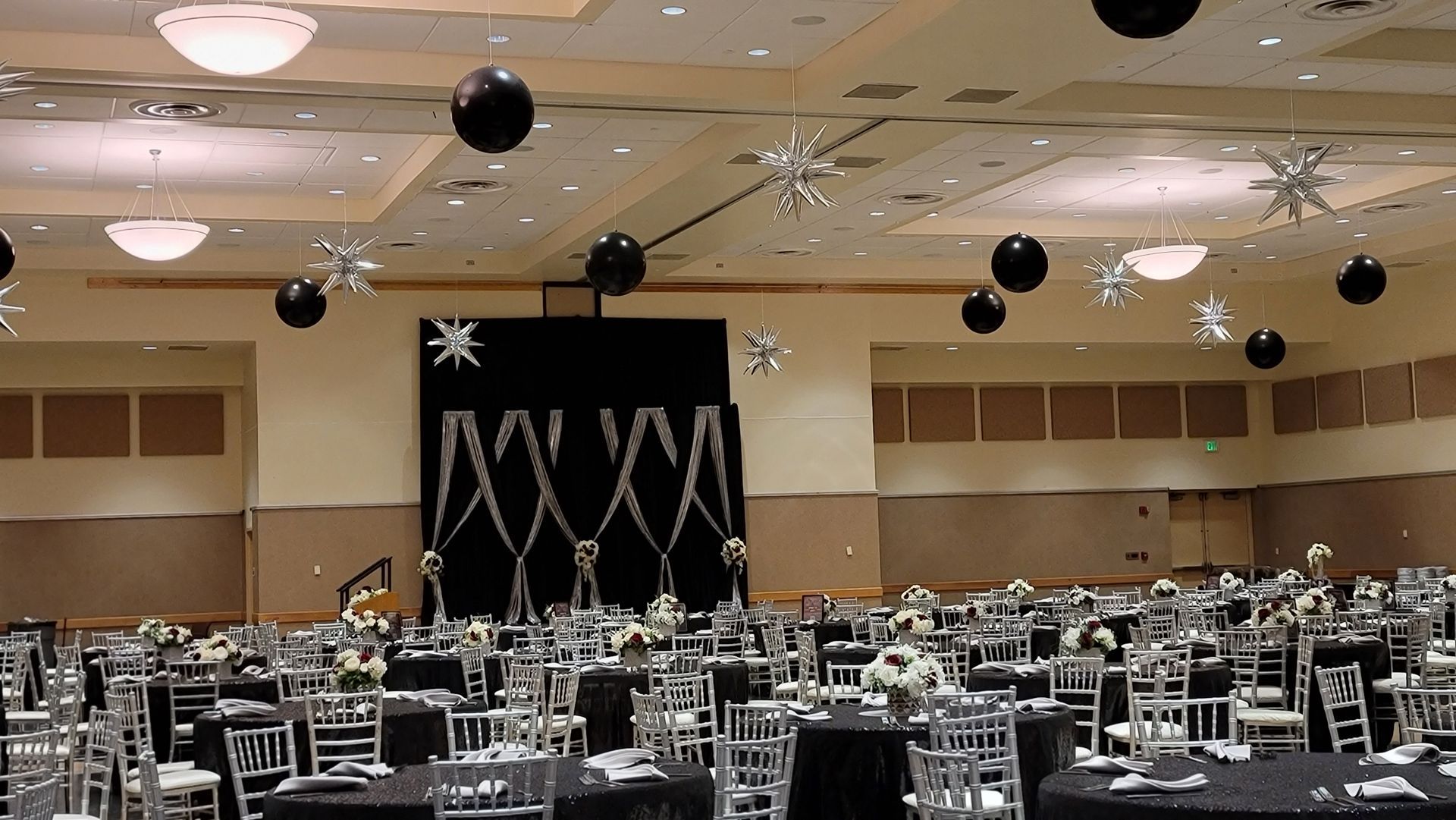 a large room with tables and chairs and balloons hanging from the ceiling