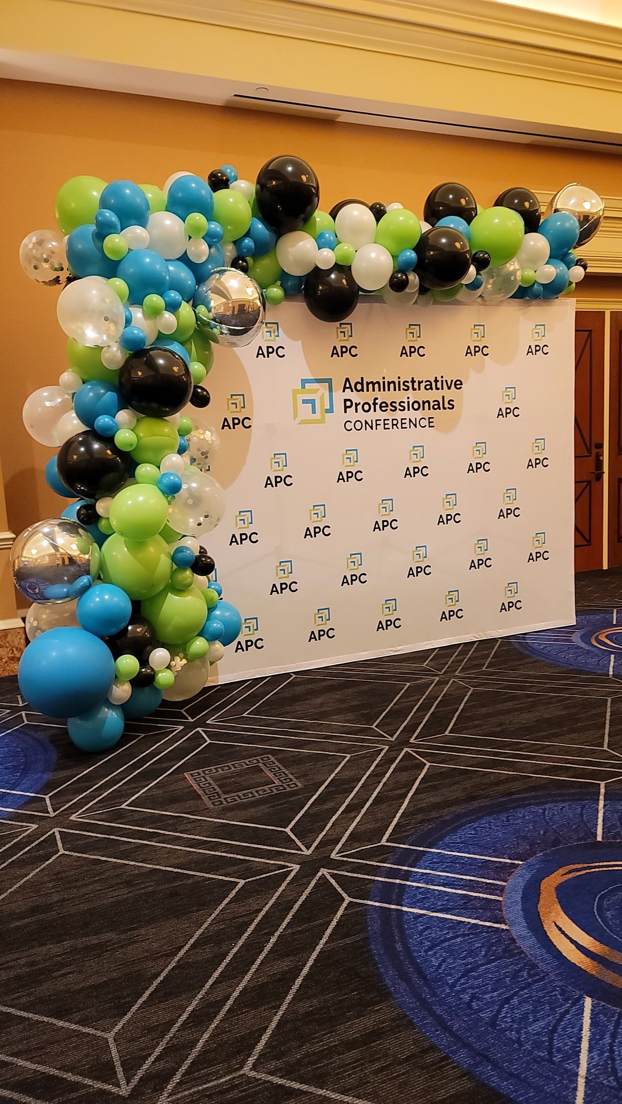 a room filled with blue , green , and black balloons .