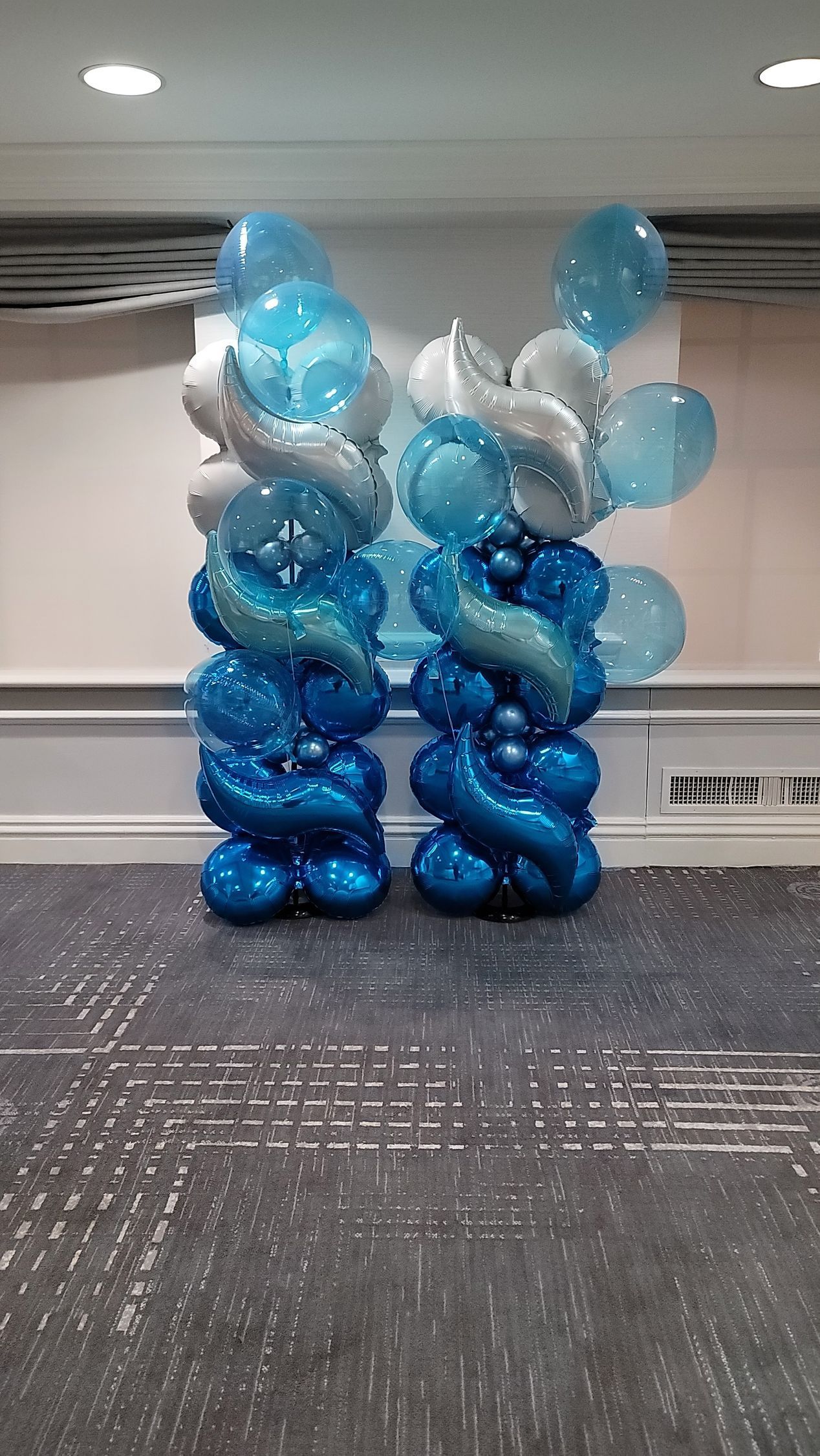 two columns of blue and white balloons in a room .