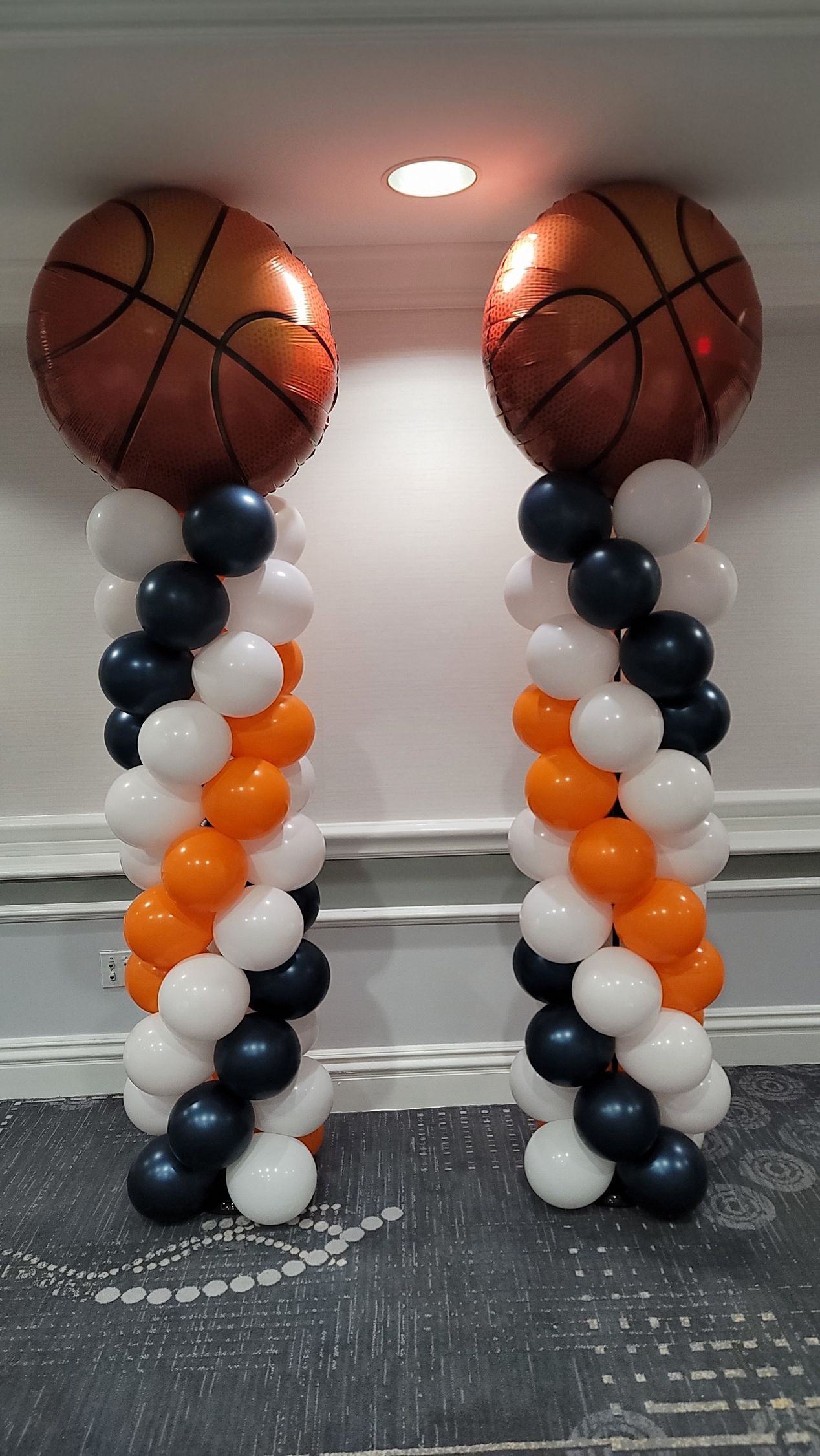 two columns of balloons with basketballs on top of them .