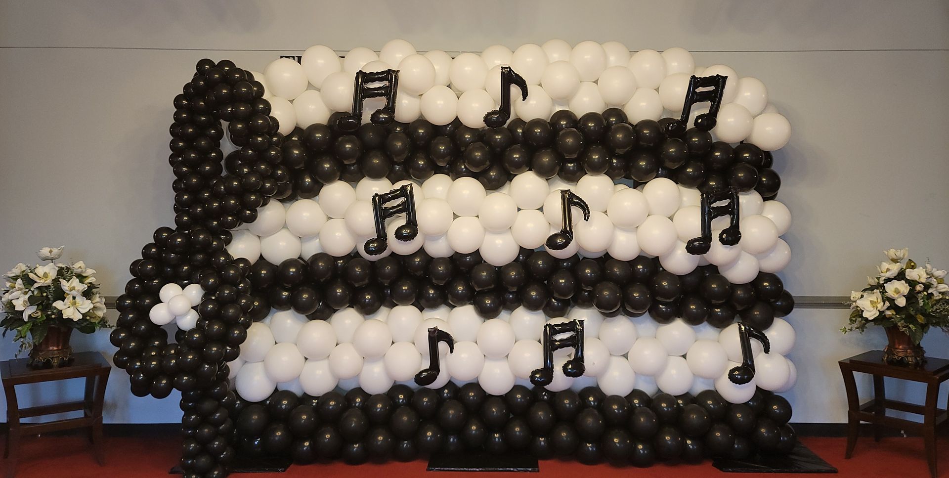 a wall made of black and white balloons with music notes on it