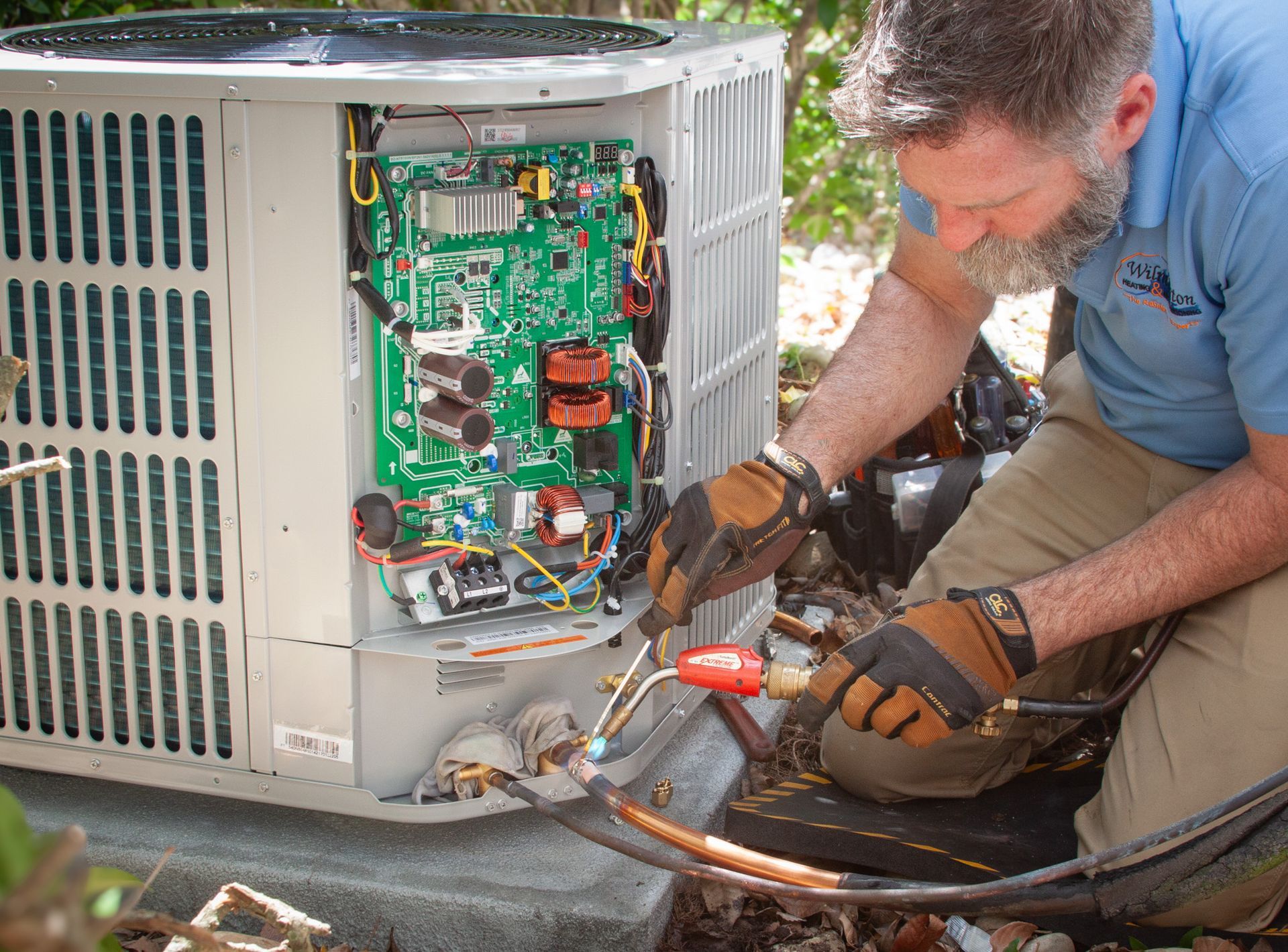 A man is working on an air conditioner with a torch. Heat Pump Repair Service Wilmington NC
