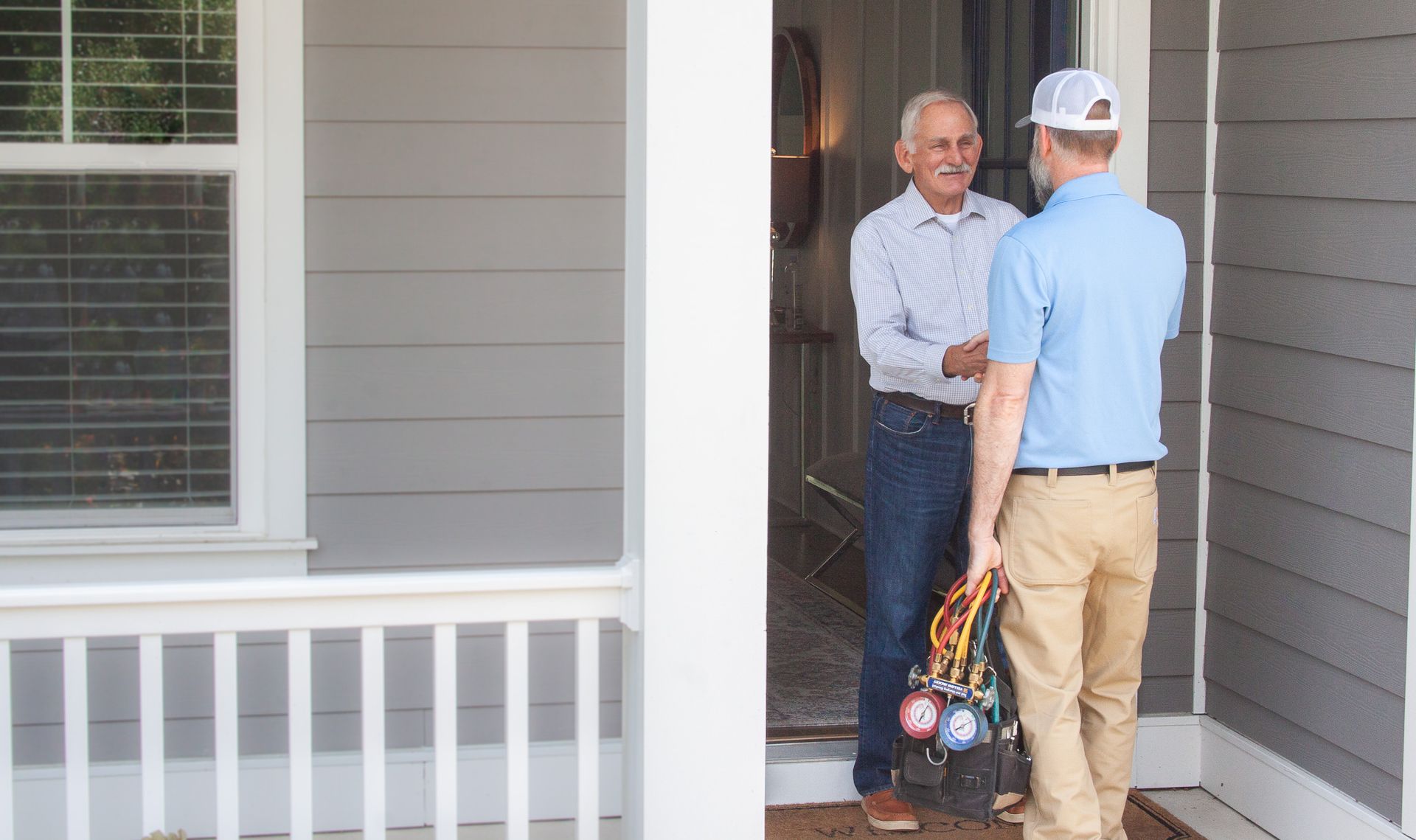 A man is shaking hands with a plumber in front of a house. Wilmington Heating & Air Conditioning Inc Provides HVAC Services in Wilmington, NC Call 910-515-0870