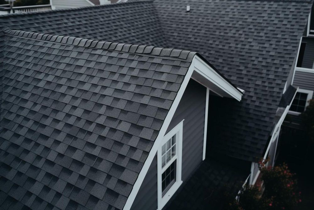 Gray shingled house roof with white trim and a dormer window, viewed from above