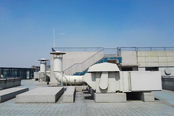 Rooftop with white HVAC units, ducts, and vents under a clear blue sky.