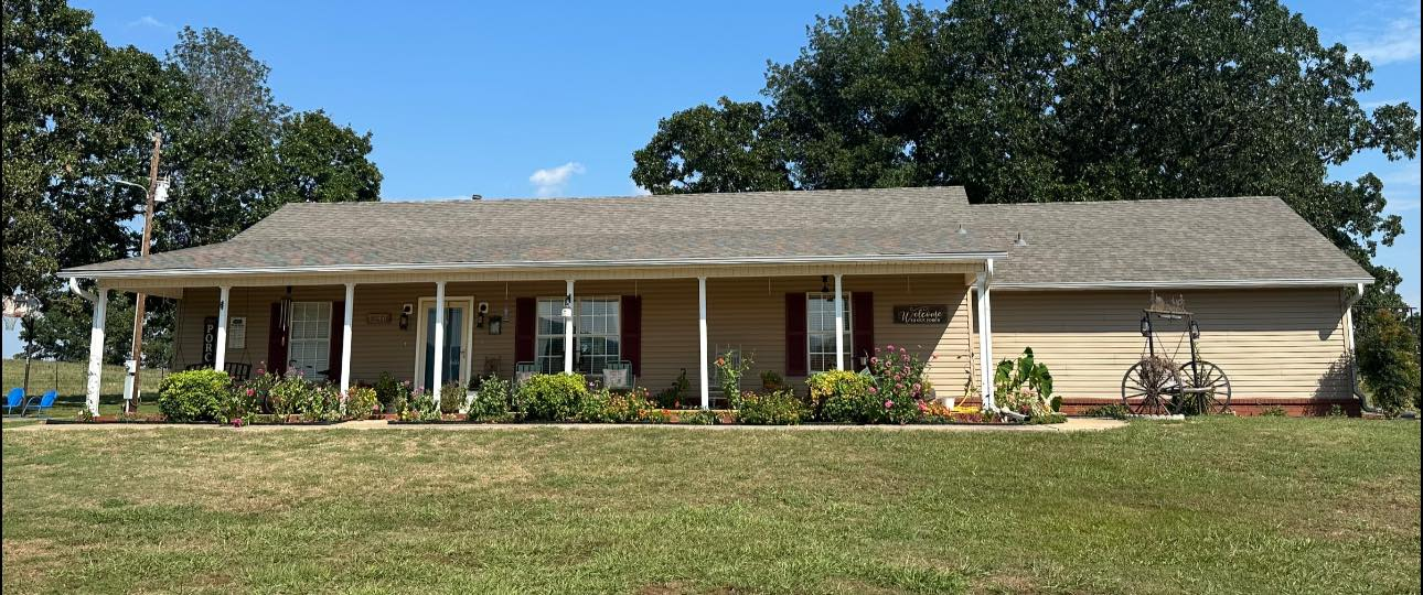 Single-story beige ranch house with a front porch and a bicycle in the yard