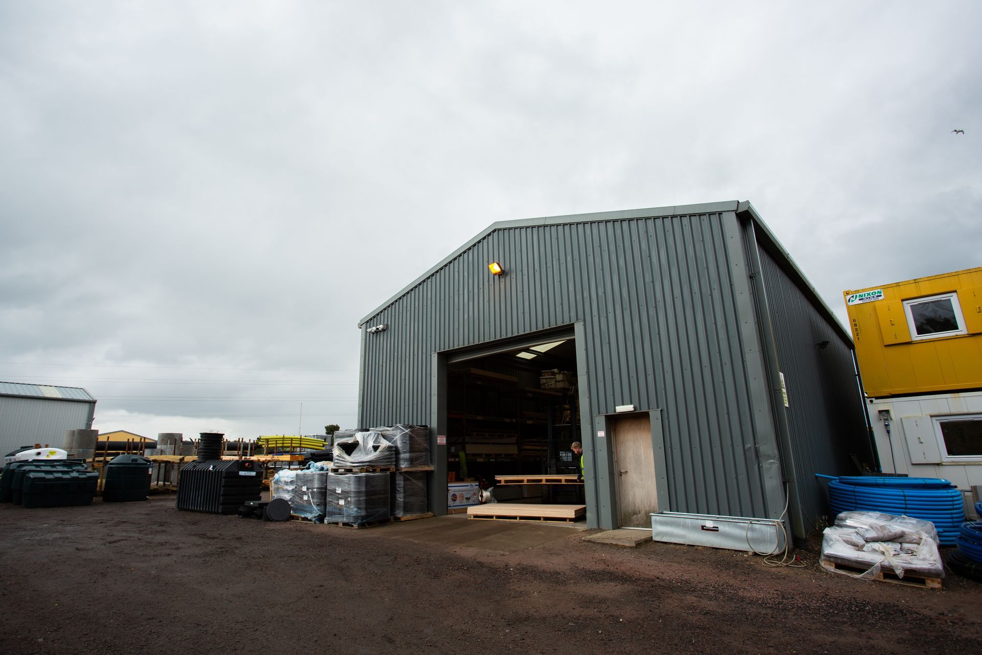 A large warehouse with a large door is surrounded by a lot of containers.