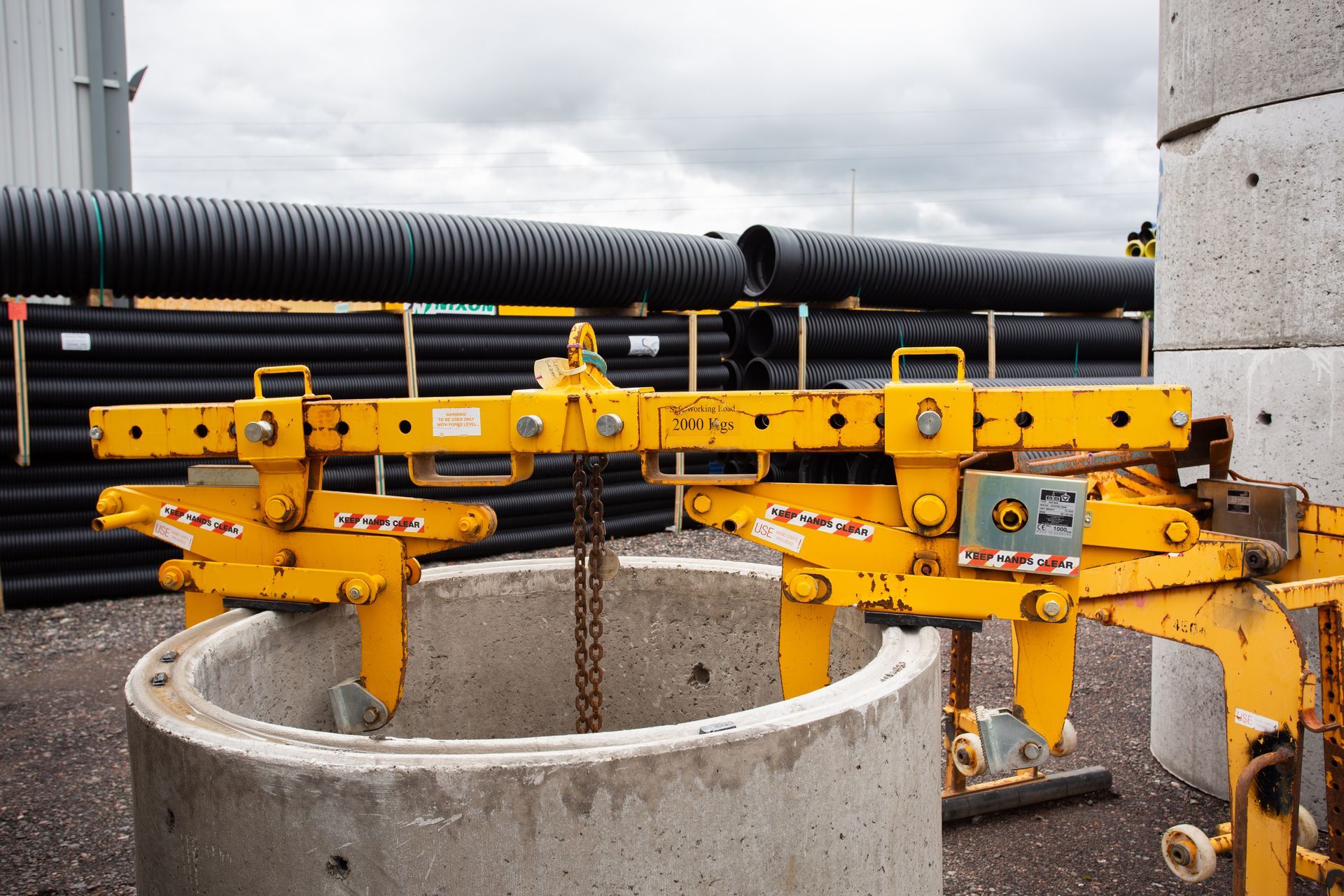 A yellow crane is lifting a concrete ring.